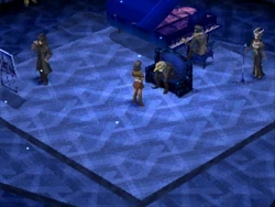 A blue room with curious rotating arrow-patterns on the floor. Igor the old man sits on a chair before the protagonist. Nameless the pianist is in the back, playing the piano. Next to Igor is Belladonna, the singer, who vocalizes the iconic song of the Velvet Room. In the corner is the mysterious Demon Painter.